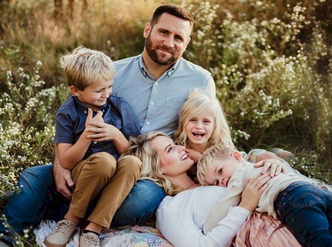 Cách tạo dáng chụp ảnh gia đình 5 người hạnh phúc khi đi chụp ngoại cảnh, đi giả ngoại, với kiểu tạo dáng này, bố ngồi mẹ nằm tựa đầu lên đùi bố, hai bé lớn ngồi vào lòng bố, em bé nhỏ thì nằm trên người của mẹ, cả nhà cùng cười tươi vui vẻ. 