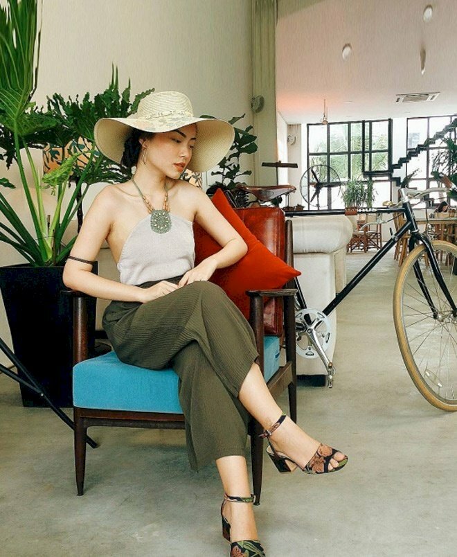 Tạo dáng chụp ảnh ngồi trên ghế với hai chân bắt chéo lên nhau, người ngồi hơi nghiêng, hai tay đặt lên đùi.
