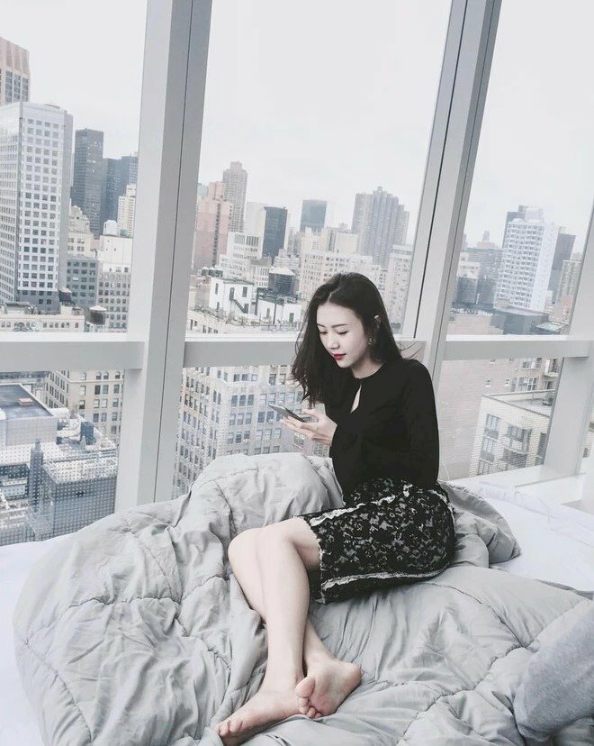 Cách tạo dáng chụp ảnh trong phòng ngủ với tư thế ngồi nghiêng 1 bên người, đặt chân này xéo qua chân kia, với 1 tay chống xuống giường.