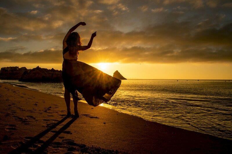 Cách tạo dáng khi chụp ảnh ở biển với chiếc váy mỏng, 2 tay đưa lên cao như đang nhảy múa dưới bình minh vàng rực