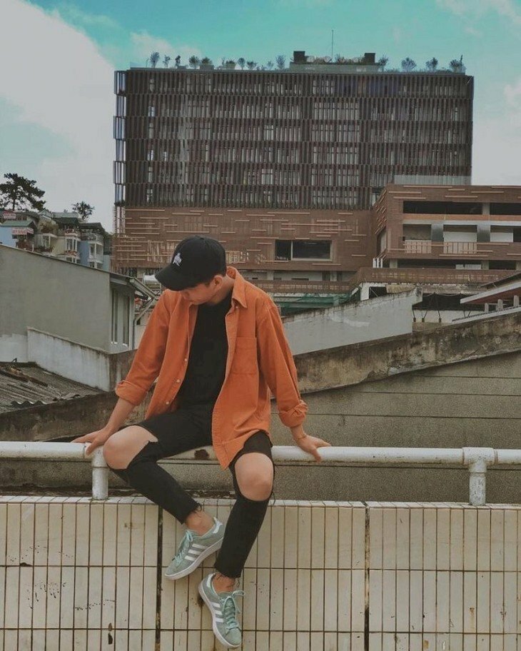 Kiểu tạo dáng nam thần thái lạnh lùng đang ngồi trong chiếc áo nâu đỏ mắt nhìn một bên đầu hơi cúi, 2 tay nắm thành phía sau