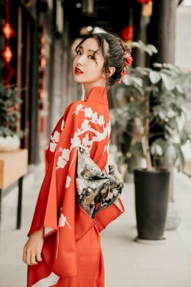 Tạo dáng xinh xắn dịu dàng trong chiếc áo truyền thống của xứ sở Phù Tang màu đỏ tươi ở góc chụp một bên, người hơi ngửa về sau, mắt nhìn ống kính