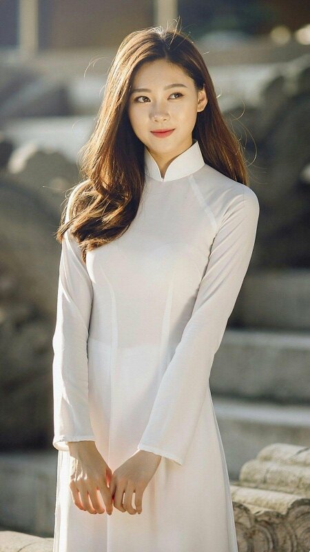 Tạo dáng cute, ngây thơ với mặt hướng nghiêng, mắt liếc nhìn xa, miệng cười mỉm, 2 tay khẽ chạm nhau phía trước