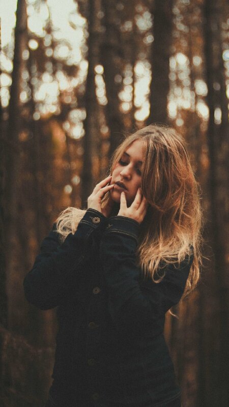 Tạo dáng nữ cute khi chụp ngoại cảnh với dáng người đứng thẳng tự nhiên, vai hơi nghiêng một bên nét diễn nhắm mắt và 2 tay chạm nhẹ lên mặt