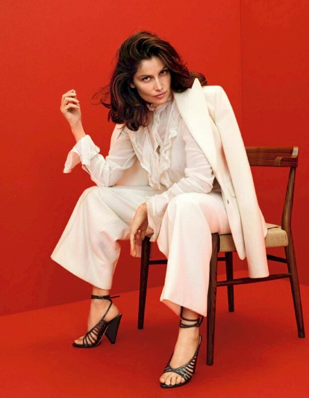 Tạo dáng sang chảnh và năng động trong kiểu ngồi ghế tự nhiên, áo khoác vai phía sau, cánh tay ghì lên đùi, tay còn lại đưa lên chạm tóc, người hơi cúi, mắt liếc nhìn lên camera