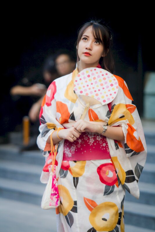 Tạo dáng chụp ảnh trong bộ Kimono Nhật Bản với 2 tay cầm chiếc quạt, đầu hơi nghiêng, mắt nhìn lên cao rất dễ thương