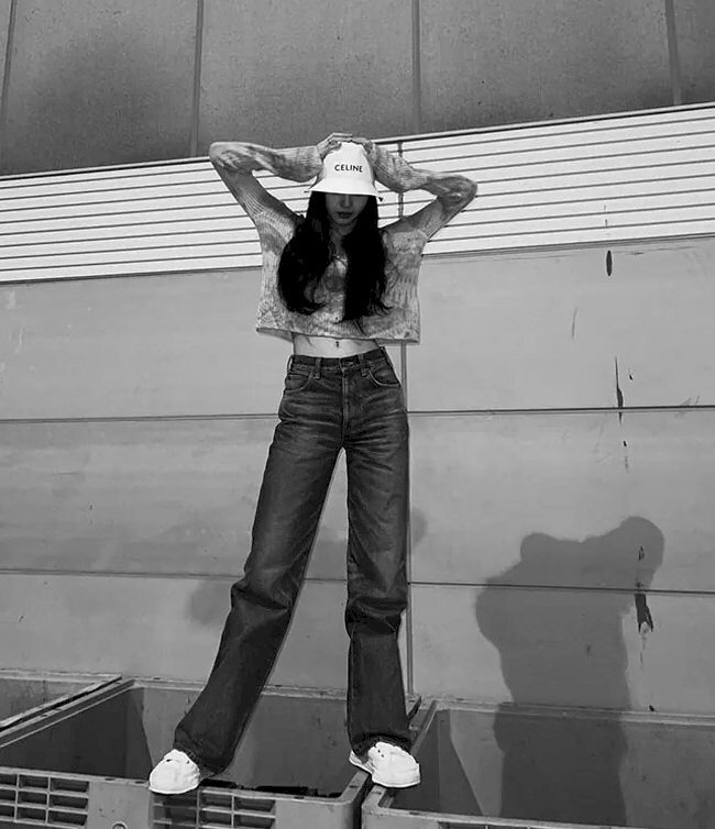 Cách tạo dáng chụp ảnh đứng ngầu cho nữ với hai chân rộng ngang vai, hai tay đặt lên đầu.