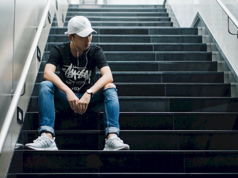 Cách tạo dáng chụp ảnh với cầu thang dành cho nam khi ngồi cầu thang cực ngầu chất đậm chất nam tính với dáng ngồi dang rộng hai chân, 2 tay để tay vòng qua đầu gối chạm vào nhau, người hơi khom lên phía trước và đầu nghiêng về 1 bên.