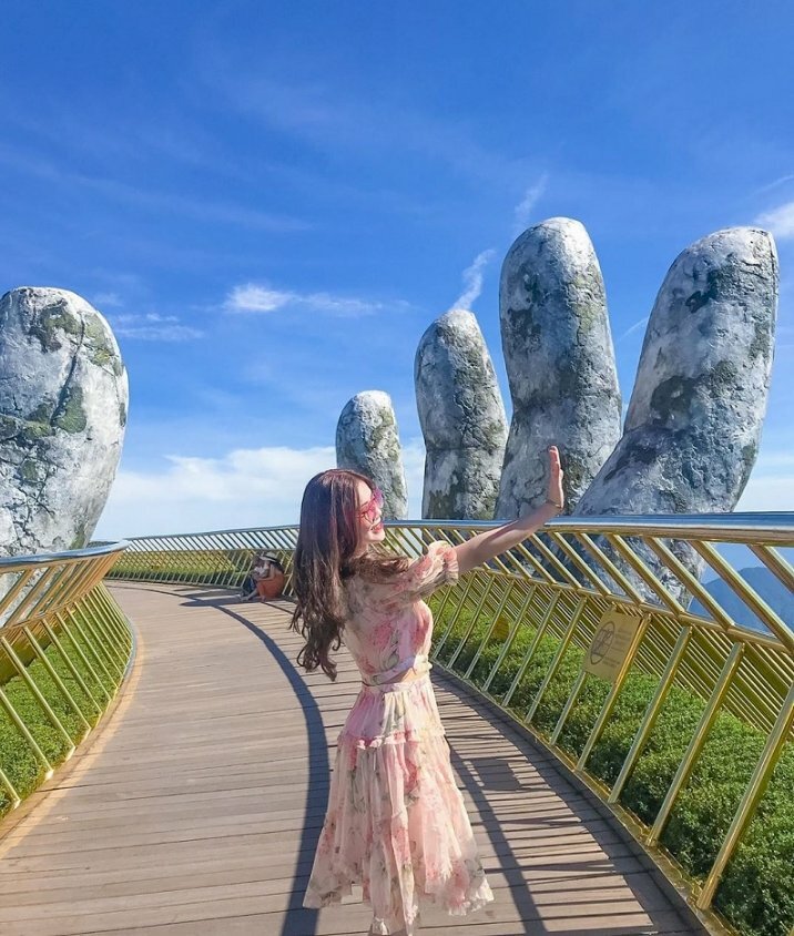 Tạo dáng siêu cute của cô gái trong chiếc đầm hoa một tay dơ cao che nắng, đứng quay người về phía mặt trời, góc chụp nghiêng tuyệt đẹp