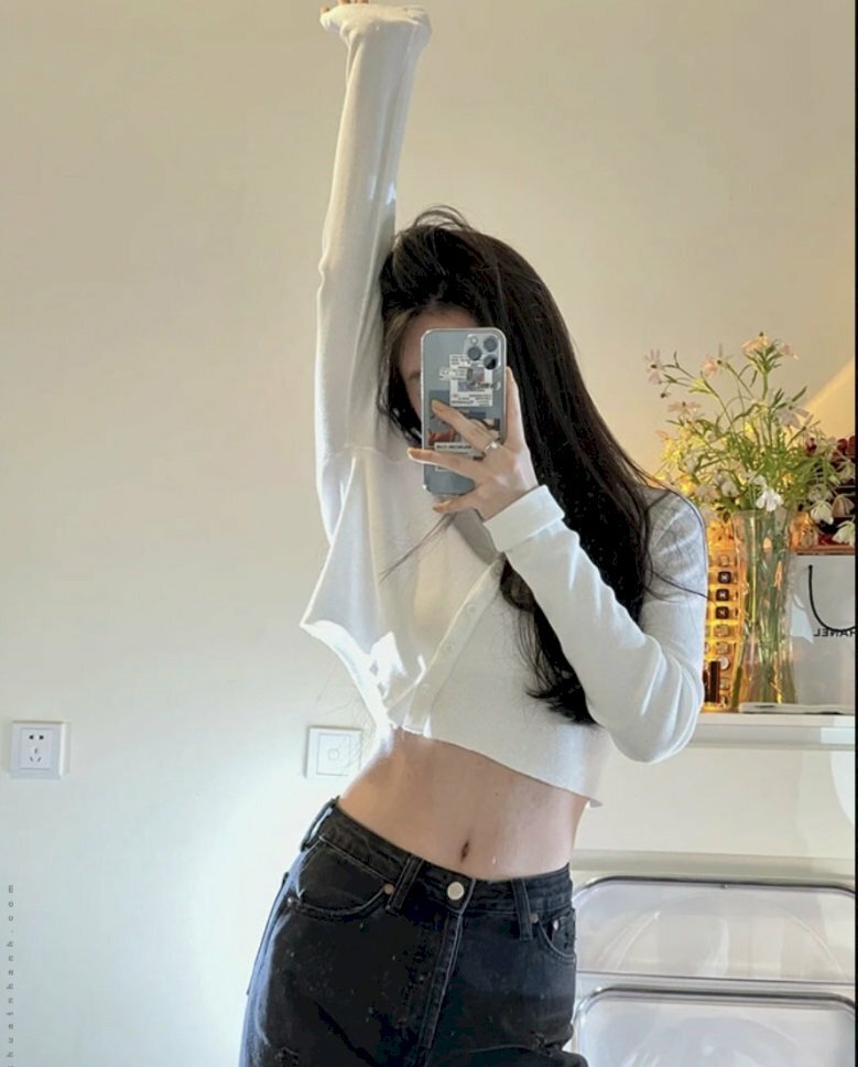 Cách chụp ảnh với áo croptop trước gương khoe vòng eo nhỏ xinh bằng cách đứng hơn đẩy nhẹ hông qua 1 bên, 1 tay đưa cao qua đầu và 1 tay cầm điện thoại đứng trước gương để chụp ảnh. 