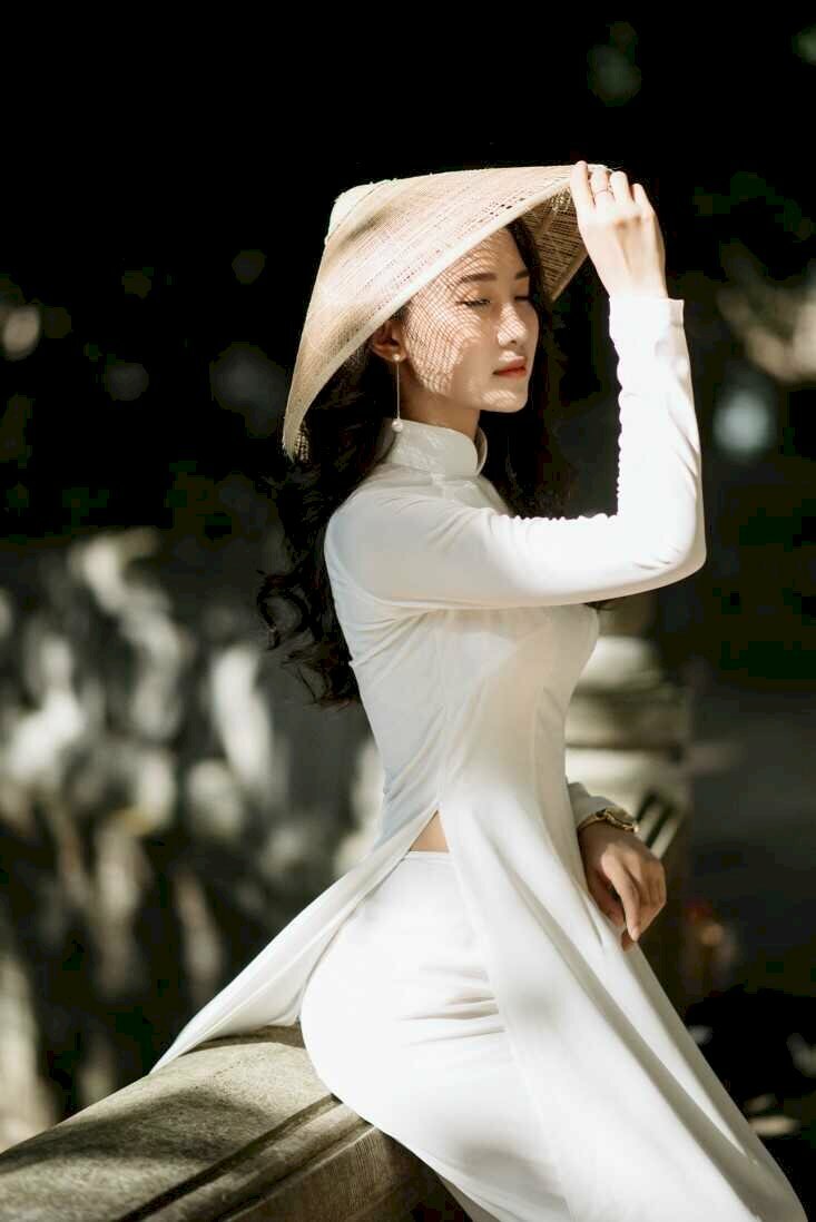 Dáng ngồi trên thềm đẹp thu hút với đôi mắt nhắm nhẹ tay chạm nón lá, tay để trước bụng