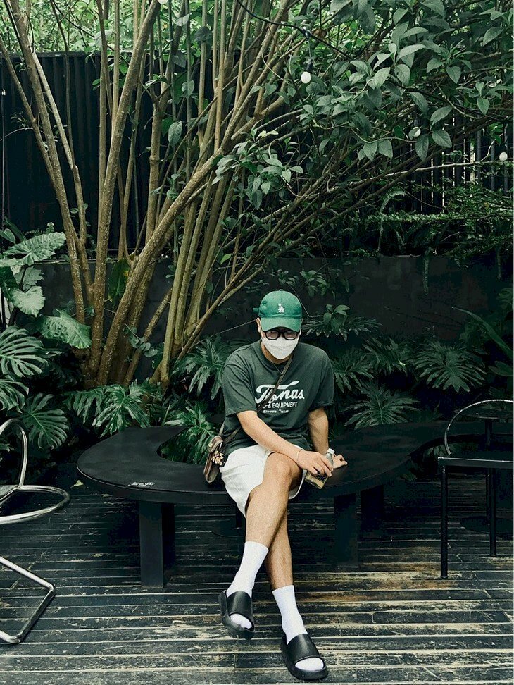 Kiểu tạo dáng nam ngồi bắt chéo chân tay cầm chai nước, tay còn lại chống phía sau mắt nhìn xuống đất toát lên vẻ lạnh lùng cực chất