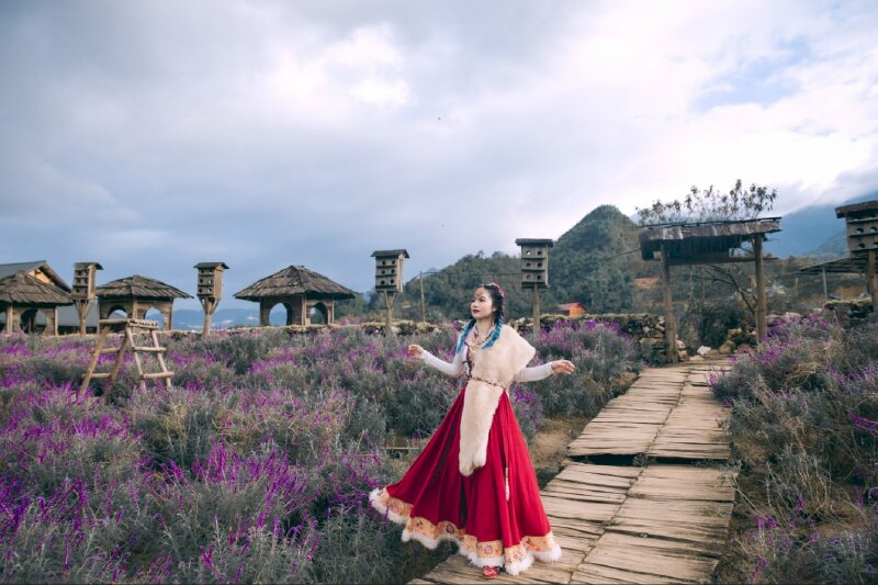 Tạo dáng tuyệt đẹp với chiếc váy truyền thống, 2 tay đưa lên tạo dáng, mắt nhìn xa, tư thế đứng như đang nhảy múa trên vườn hoa bản Cát Cát