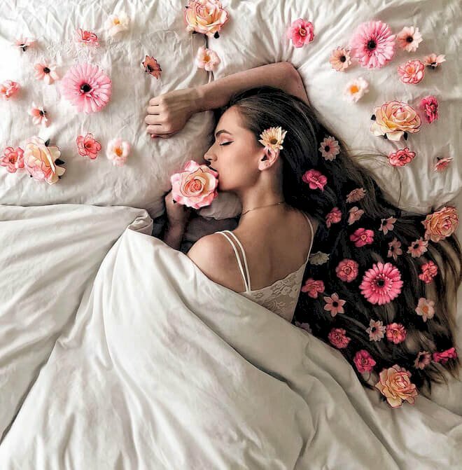 Tạo dáng thu hút và gợi cảm trên chiếc gường đầy hoa trải trên giường và tóc cô gái trong tư thế nằm nghiêng người tựa đầu lên tay, một tay cầm hoa hồng đưa lên miệng rất đẹp và nghệ thuật.