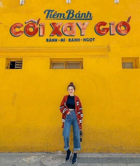 Cách tạo dáng chụp ảnh đứng ngầu cho nữ với 1 tay để vào túi quần, 1 tay thả lỏng, người dựa vào tường.