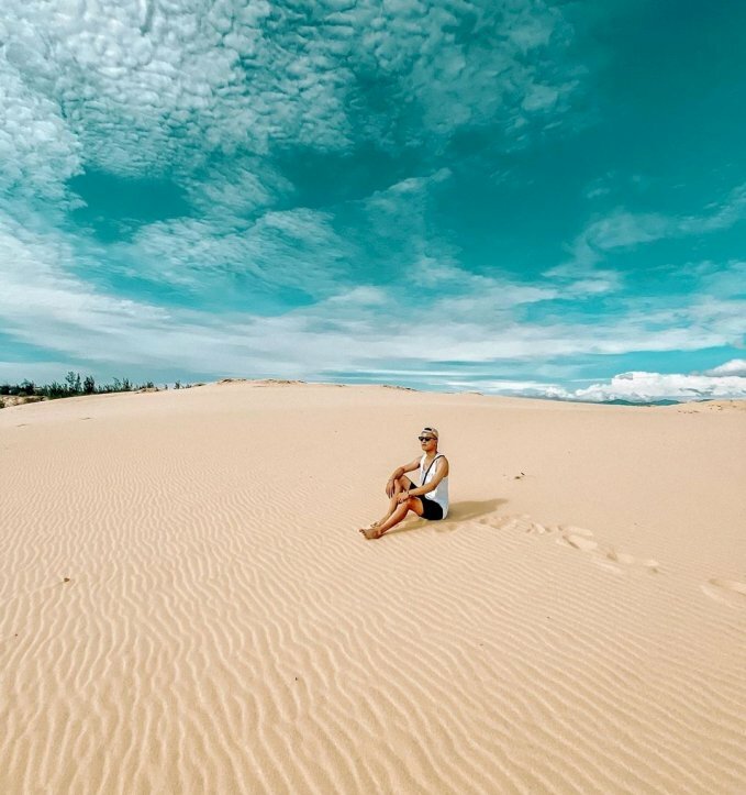 Cách tạo dáng chụp ảnh trên đồi cát cho nam ngầu chất với kiểu này hãy ngồi thẳng lưng xuống cát, đặt 1 chân trước 1 chân sau hơi co vào người và 2 tay đặt trên hai chân, với gương mặt ngước lên nhìn phía trước.
