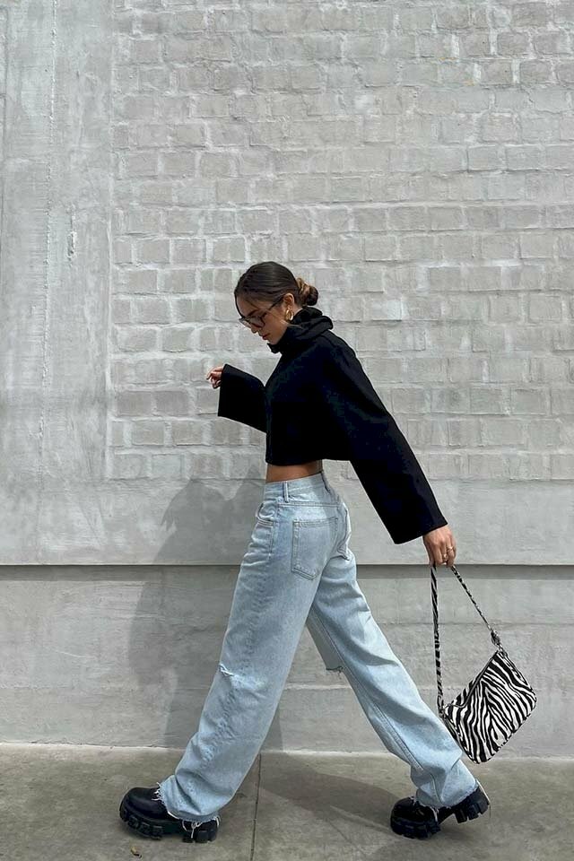 Cách tạo dáng chụp ảnh với áo croptop khi đang bước đi dành cho cô nàng mặc outfit ngầu chất gồm áo croptop màu đen tay dài cổ lọ cùng chiếc quần jean ống đứng kết hợp cùng đôi giày oxford đế cao màu đen. Với dáng chụp như đang bước đi hãy bước chân trái dài lên phía trước, chân phải sau, tay trái thì vung mạnh về phía sau song song với chân phải, và tay phải thì đưa lên tầm ngang ngực, đầu cúi xuống nhìn vào chân.