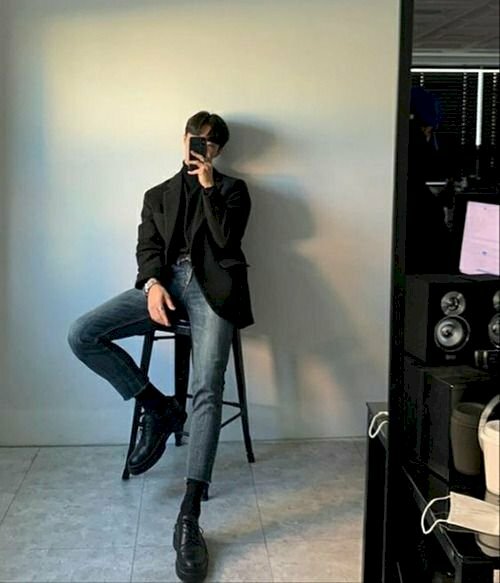 Cách tạo dáng chụp ảnh cho nam gầy khi chụp trước gương với dáng ngồi trên ghế cao, lưng tựa vào tường, chân để 1 chân thẳng, 1 chân co lên gác trên bậc trên ghế. 