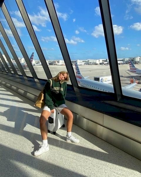 Cách tạo dáng chụp ảnh ở sân bay cho nữ khi ngồi trên vali cực kỳ đơn giản với dáng ngồi dang rộng hai chân, đặt một tay ra phía trước vali, một tay chống phía sau và nghiêng đầu về một bên.