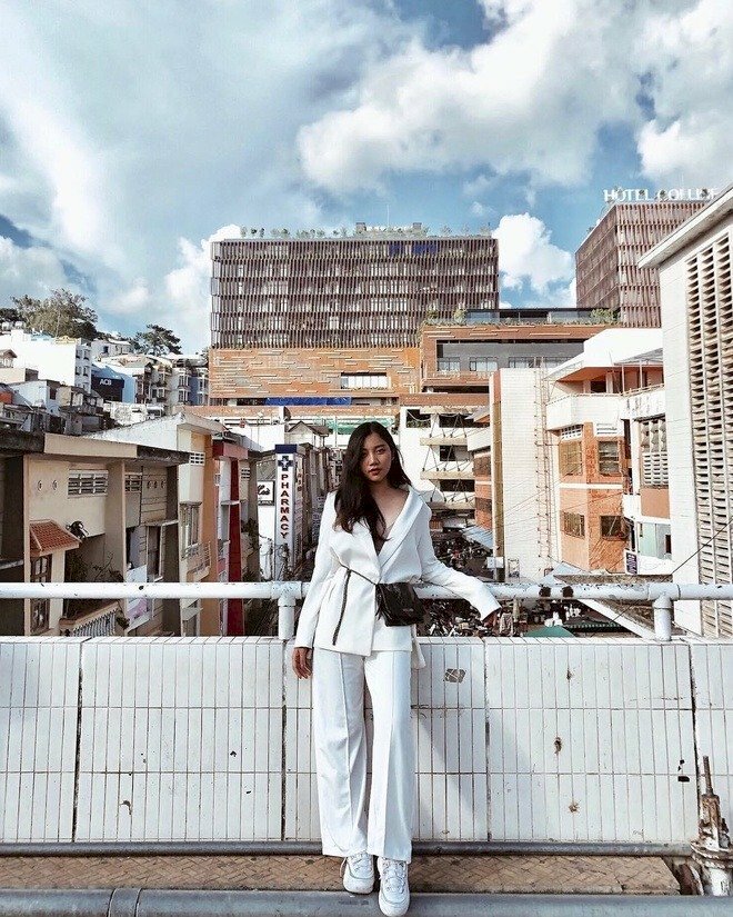 Tạo dáng đứng với một chân hơi khuỵu nhẹ, một chân thẳng tự nhiên, một tay gác lên lan can, một tay buông thẳng, mắt hướng ống kính