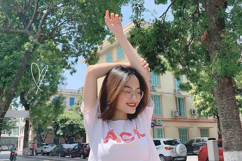 Tạo dáng một tay đưa lên cao khỏi đầu, tay kia vòng qua ôm tay đưa lên, hướng mặt hơi nghiêng, miệng cười tươi, mắt nhắm tự nhiên