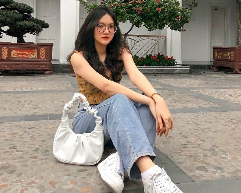 Tạo dáng ngồi bệt trên nền đất một chân co một chân duỗi, người hơi ngả về phía sau, hai tay chéo nhẹ đặt trên gối, mặt hướng thẳng ống kính