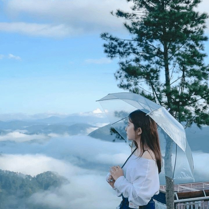 Tạo dáng đứng nghiêng với hai tay cầm đưa chiếc dù phía sau, mắt hướng nhìn về những đám mây