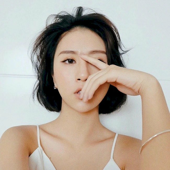 Tạo dáng chụp ảnh dùng tay che mặt, biểu cảm mắt nhìn hướng ra xa, môi hơi hở