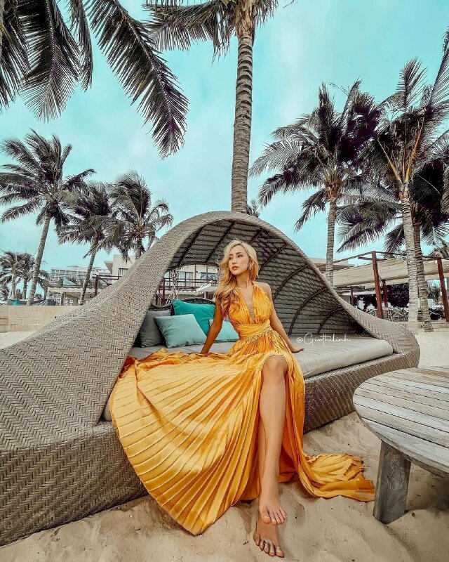 Tạo dáng ngồi với hai chân bắt chéo, hai tay chống nhẹ phía sau, người hơi ngả về sau, mặt quay nghiêng nhìn về một phía