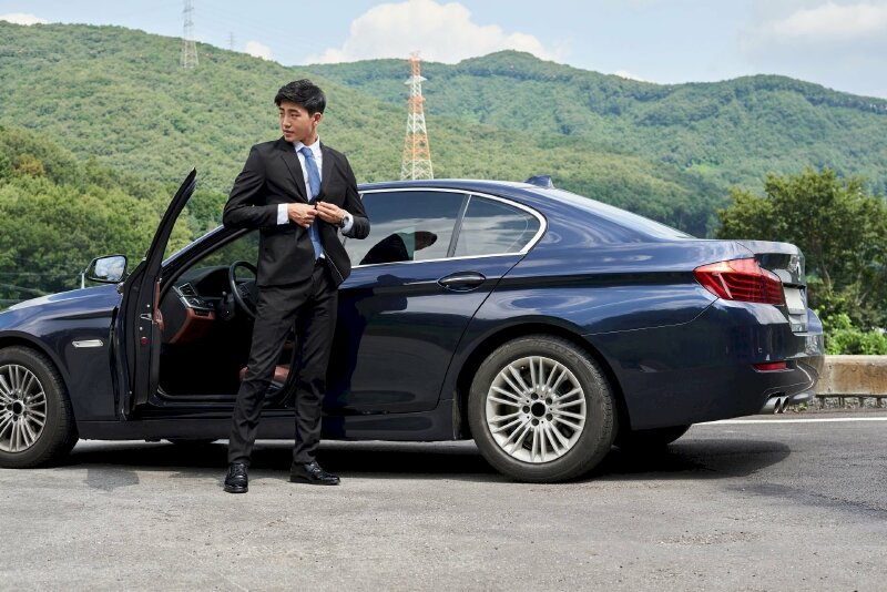 Tạo dáng như vừa bước xuống xe ô tô, hai tai cài áo, chân đứng chữ A, mặt nhìn nghiêng hướng sang một bên