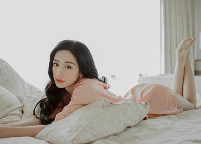 Tạo dáng nằm sấp trên giường, xoãi nhẹ hai tay về trước, hai chân co lên đan chéo bàn chân vào nhau, nhìn thằng ống kính với ánh mắt hút hồn