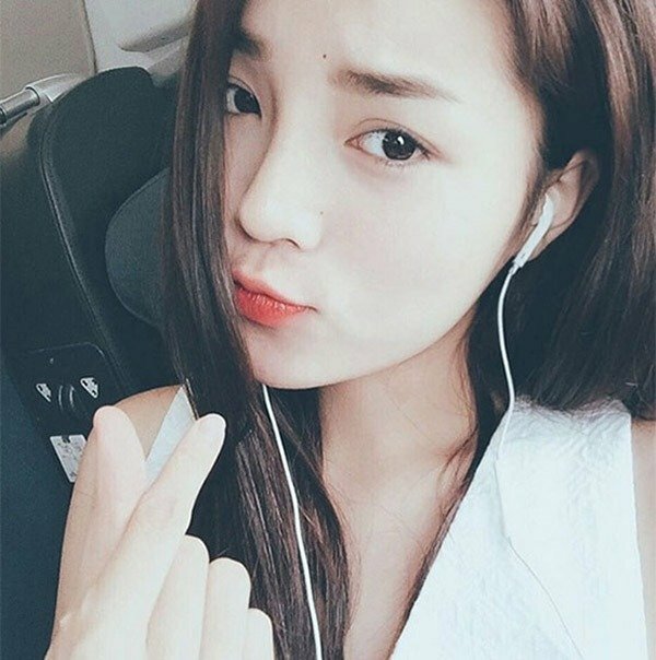 Tạo dáng hơi nghiêng đầu, môi chúm chím, tay bắn tim