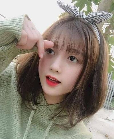 Tạo dáng không nhìn ống kính, tay đưa lên trước mặt bắn tim, miệng chúm chím cười