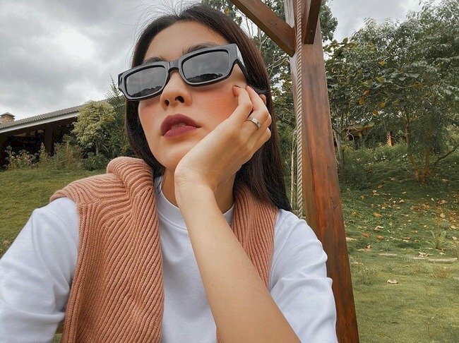 Chụp ảnh selfie với mắt kính đen, tay chống cầm, cằm hướng về phía trước, mắt không nhìn ống kính