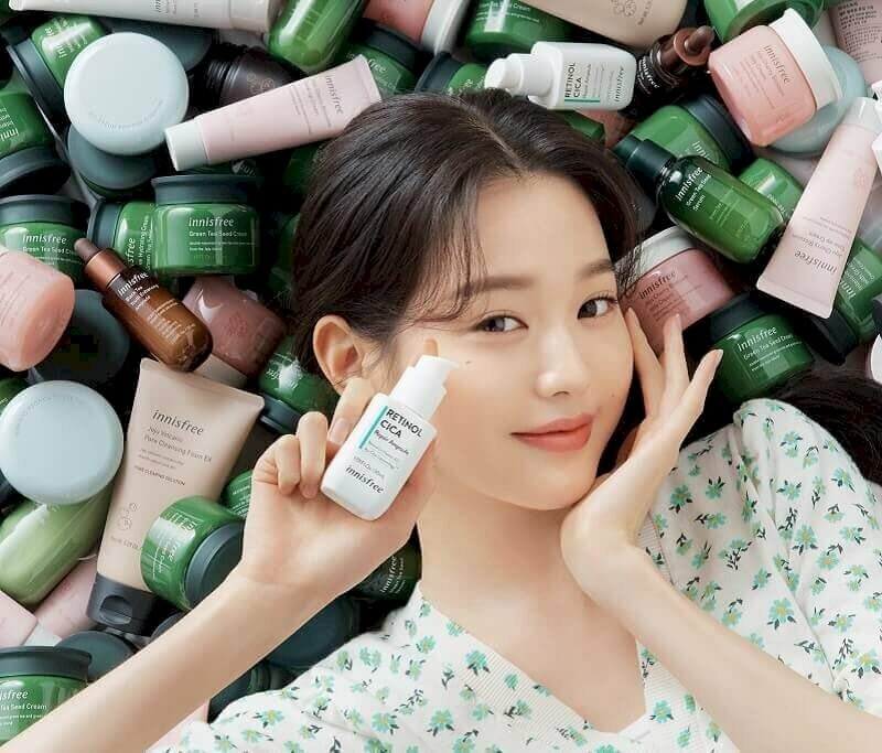 Người mẫu tạo dáng như đang nằm với background là tất cả các sản phẩm mỹ phẩm của thương hiệu thực hiện ảnh quảng cáo