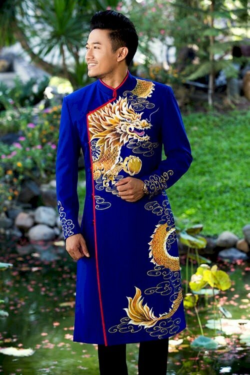 Phong thái tạo dáng nam đứng một tay đặt vuông góc trước ngực, một tay duỗi thẳng, mặt hướng nhìn về một phía cùng nụ cười tự tin