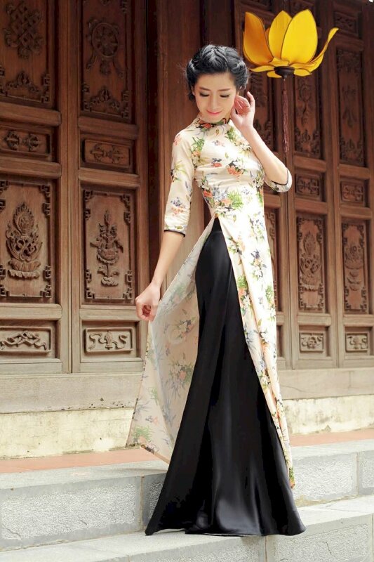 Tạo dáng đứng nghiêng về một phía, một tay nắm nhẹ tà áo, một tay đưa lên đặt nhẹ gần tai, khuôn mặt hướng xuống phía tay cầm tà áo, miệng cười thật duyên