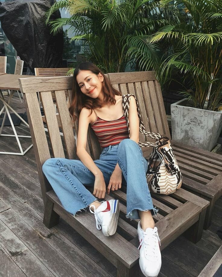 Tạo dáng ngồi trên ghế tư thế dựa vào lưng ghế, một chân co xếp bằng, một chân co chống lê ghế, hai tay để tự nhiên, đầu nghiêng nhẹ vào thành ghế và nhìn ống kính máy ảnh