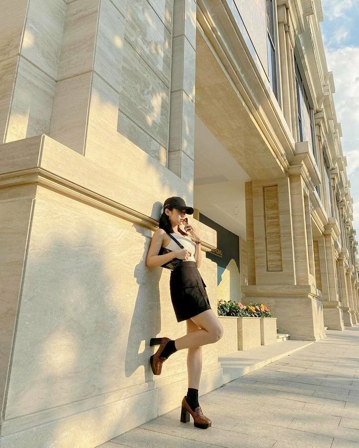 Cách tạo dáng đứng dựa tường, hơi ngả người, một chân co, phối váy ngắn cùng phụ kiện chụp ảnh đẹp cool