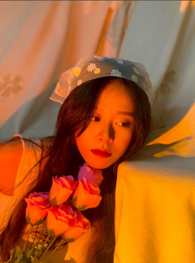 Cách tạo dáng với bó hoa hồng tuyệt đẹp mặt tựa nhẹ vào bàn, mắt liếc nhìn sang trái cùng với hiệu ứng đèn vàng tạo một bức hình đẹp và dễ thương