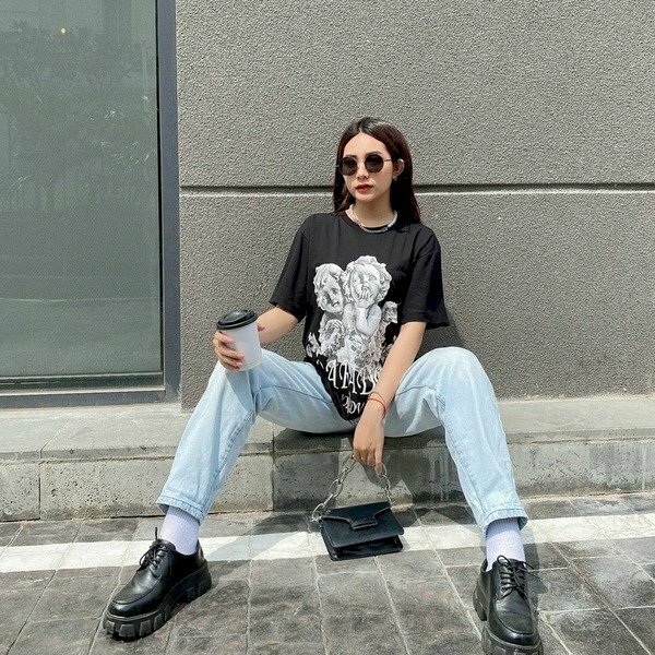 Mẫu tạo dáng ngồi 02 chân dang rộng với trang phục quần jean, áo thun, mặt hướng tự tin