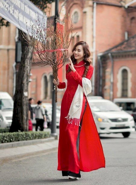 Tạo dáng bước đi thật nhẹ nhàng, tay cầm nhành đào, mặt nhìn hoa cười duyên dáng