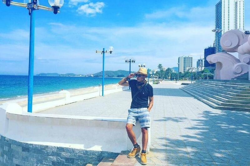 Tạo dáng ngồi ngắm biển trên bờ kè dọc bãi biển thật tự nhiên