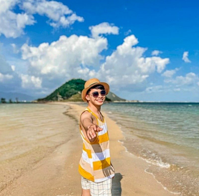 Tạo dáng chụp ảnh đi dạo biển với mặt cười thật tươi hướng về phía ống kính, tay đưa ra như muốn nắm tay một ai đó