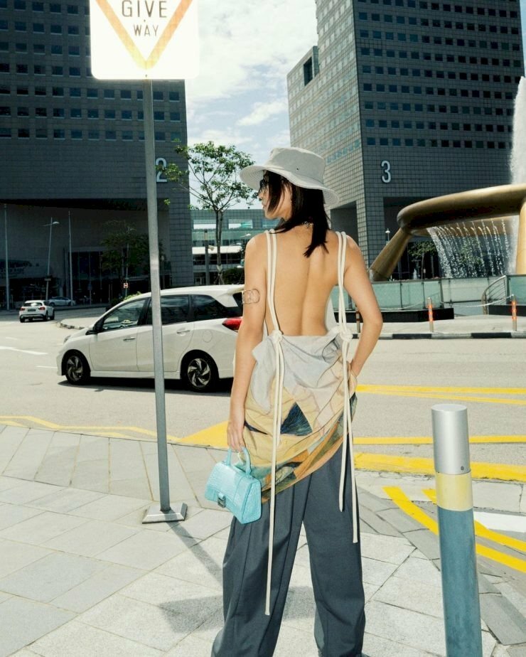 Góc chụp ảnh từ phía sau lưng với tạo dáng đứng chân chữ A, lưng thẳng, hơi đẩy phần vai lên, mặt hơi quay nghiêng hướng mắt nhìn xa