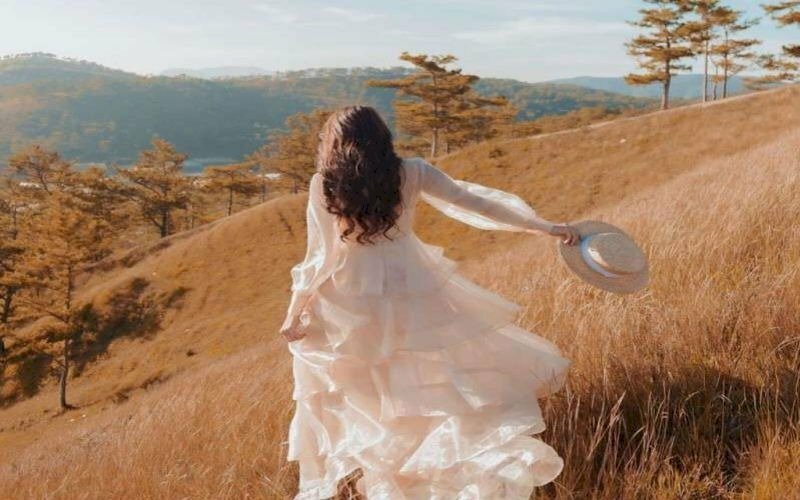 Tạo dáng chạy tung tăng trên cánh đồng cỏ, một tay nhẹ cầm váy, tóc xoã bay trong gió