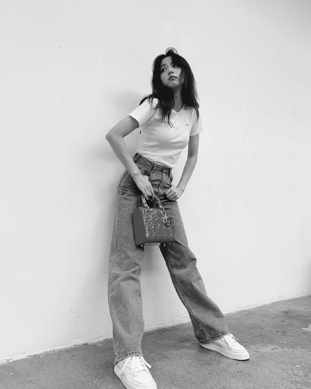 Tạo dáng đứng hai chân dang ngang, hơi dựa phần mông vào tường, người chúi nhẹ về trước, hai tay đút túi quần