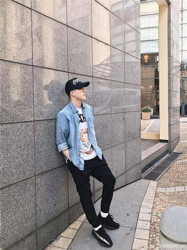 Tạo dáng đứng dựa tường, mắt hơi ngước nhìn suy tư