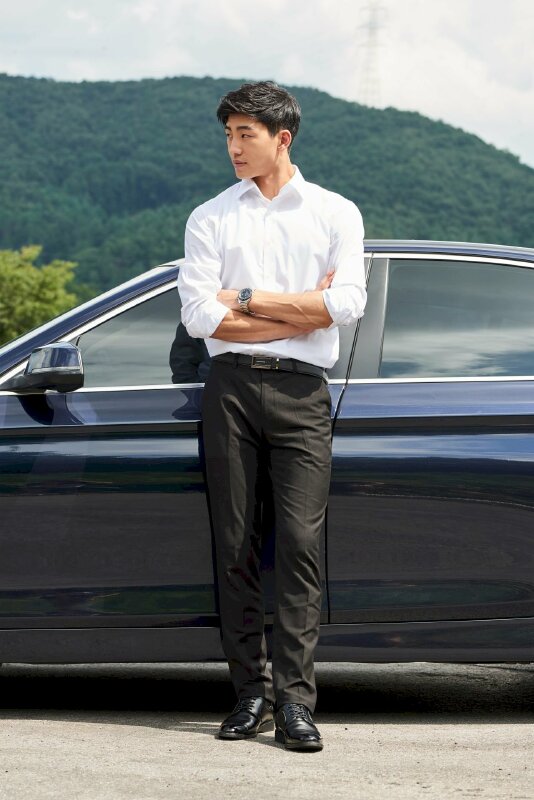 Tạo dáng đứng khoanh tay, dựa lưng vào xe hơi, mặt nhìn nghiêng sang một phía