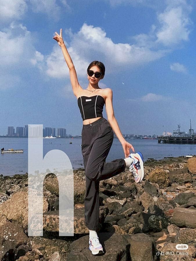 Tạo dáng đứng với một chân gập gối co lên, chân kia trụ thẳng, một tay giơ lên tạo hình 02 ngón chữ V